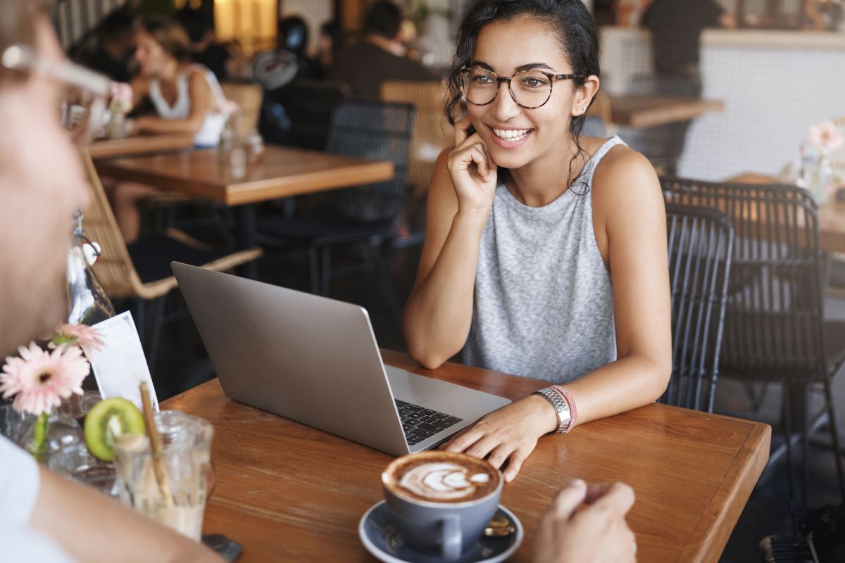 Lady at coffee shop with laptop and cappucino