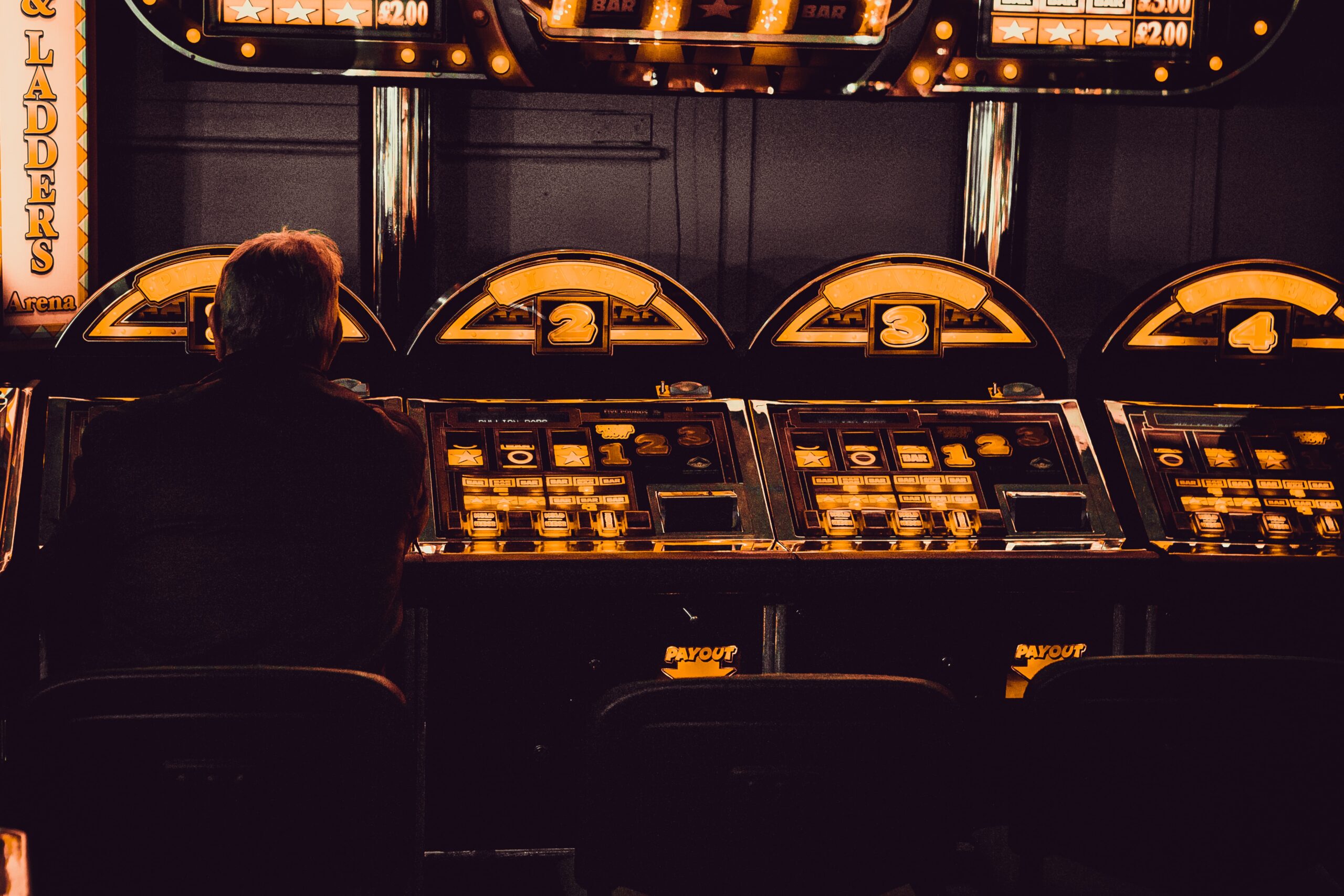 Man-playing-on-a-slot-machine-in-dark-casino