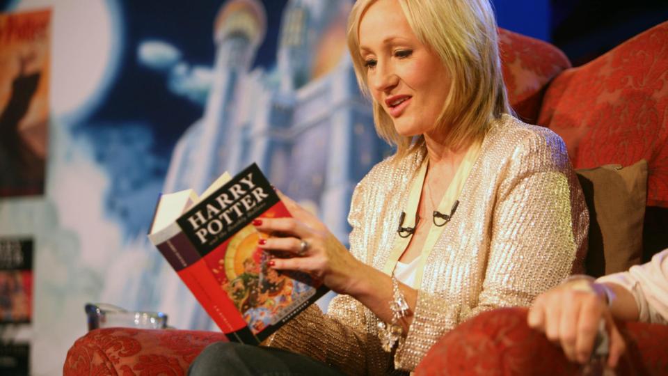JK Rowling reading from harry potter and the deathly hallows book at an event.