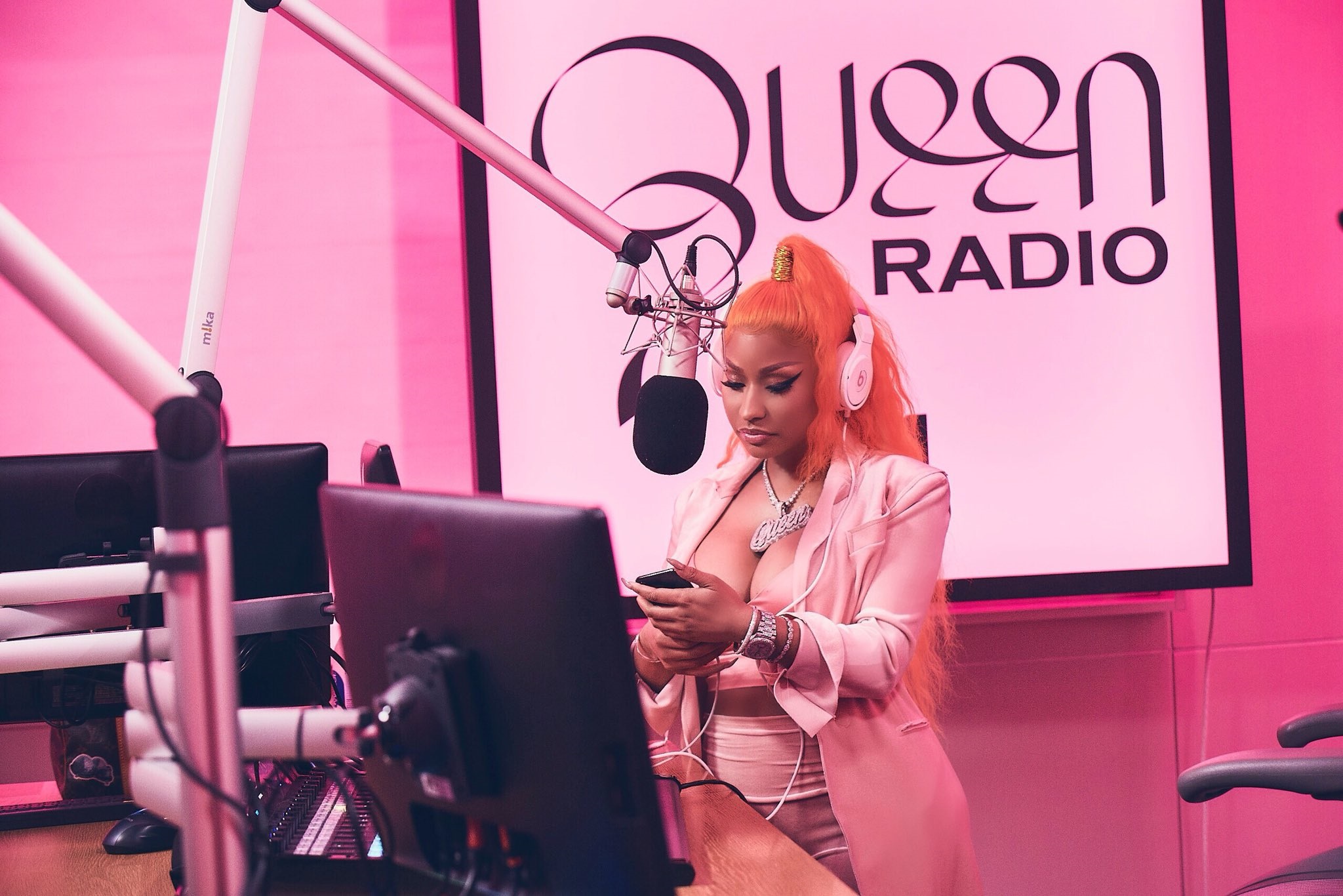 a picture of nicki minaj looking at her phone during a recording session being done for her channel Queen Radio.